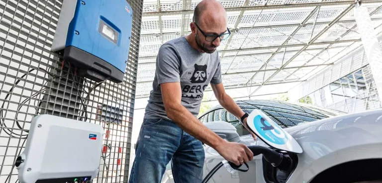 Zonne-energie Oost Nederland Man laadt een elektrische auto op bij een laadstation.